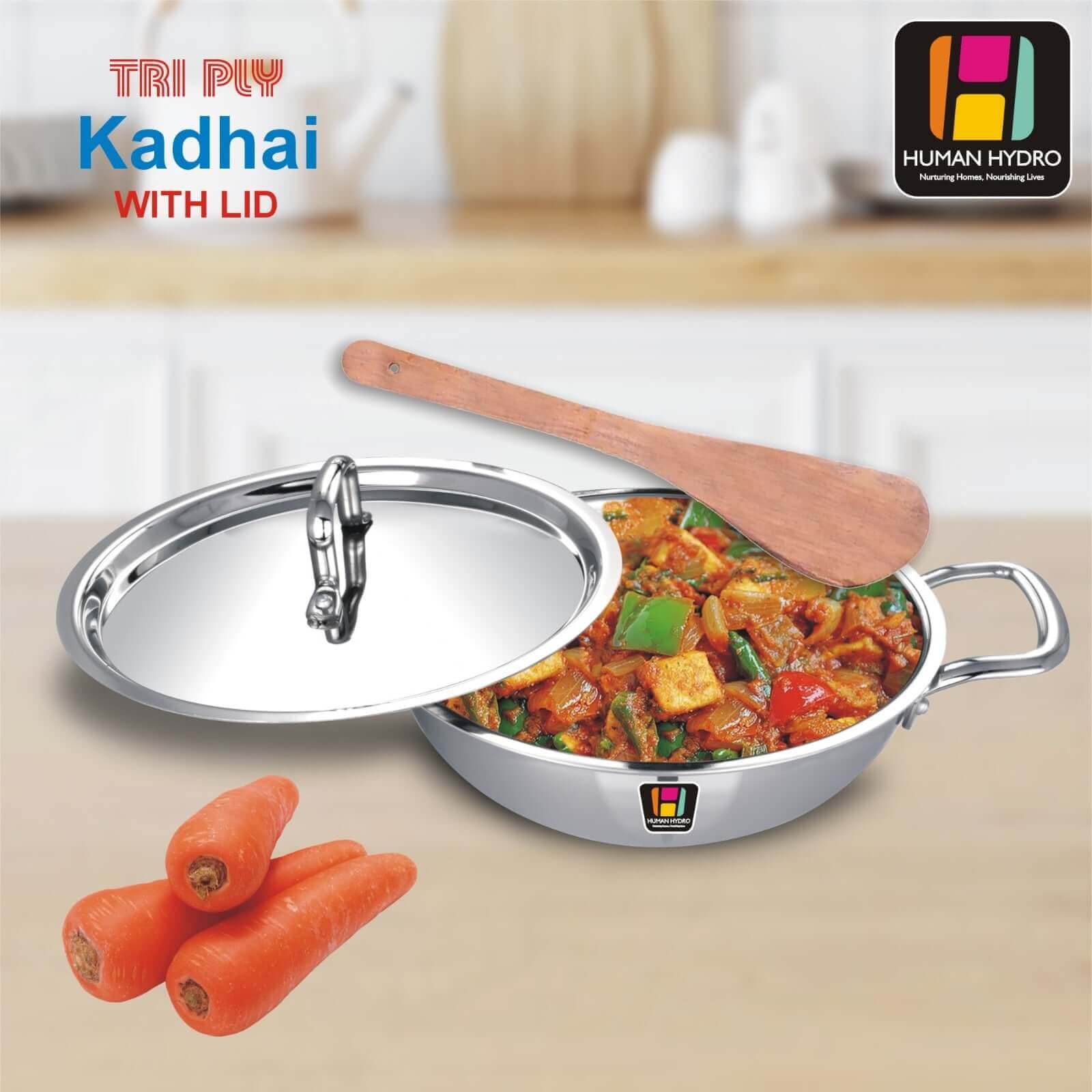 Tri-Ply Stainless Steel Kadai with lid and spatula, featuring sautéed vegetables and carrots on a kitchen countertop.