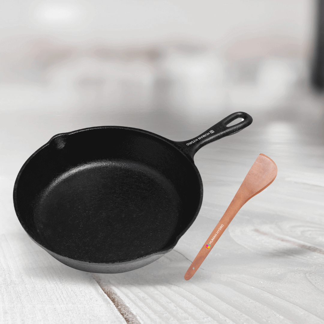 Cast iron fry pan with wooden spatula, ideal for healthy cooking and perfect for frying and searing.