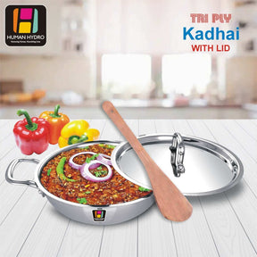 Tri-ply stainless steel kadai with lid, wooden spatula, and colorful bell peppers on display for cooking.