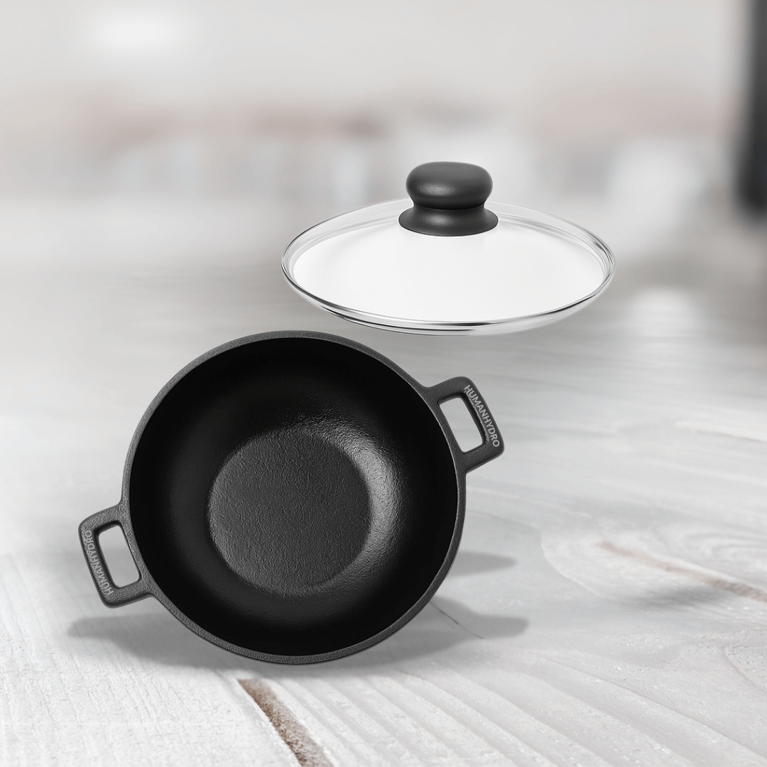Pre-seasoned cast iron kadai with glass lid, ideal for sautéing and frying, gas and induction compatible.