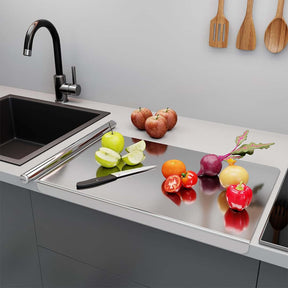 Stainless steel chopping board in kitchen with fresh fruits and vegetables, knife, and modern sink.