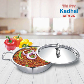 Tri-ply stainless steel kadai with lid, filled with curry, placed on a kitchen counter, showcasing cookware.
